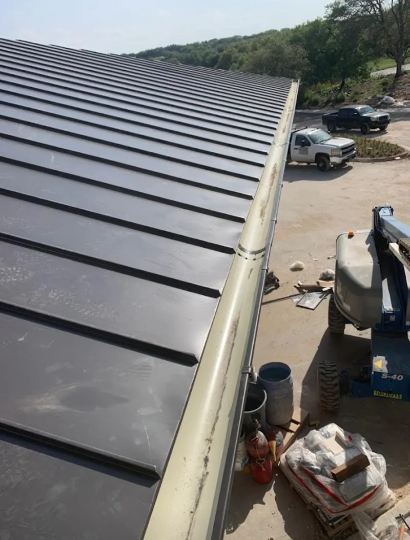 Standing seam panel and gutter detail on a metal roofing jobsite in Malvern